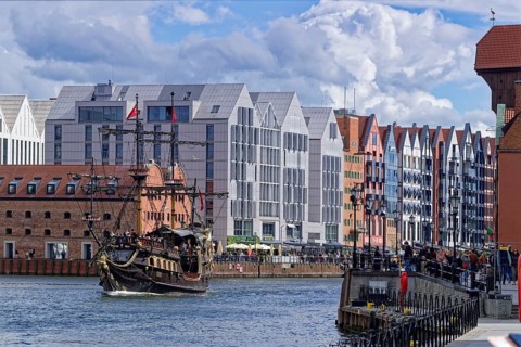 Tourists on the harbor promenade and an excursion ship designed as a pirate ship on the Motlawa in