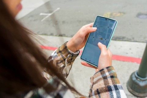 Woman standing on a san francisco street, holding a smartphone with a navigation map displaying
