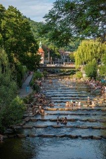 Young people sitting by and in the river, bathing in the city, heat, heat wave, climate change,