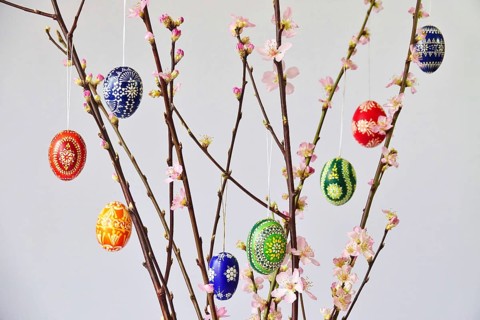 Blooming branches of a peach tree in a vase decorated with Easter eggs, spring, Germany