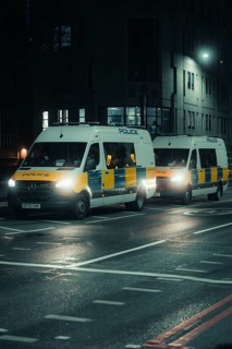 Two police vehicles on an illuminated street at night in an urban environment, New Year's Eve