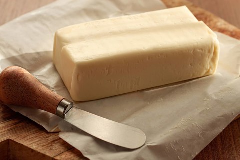 Butter briquette, on wrapping paper, wooden chopping board and butter knife, breakfast, rustic