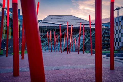 Modern architectural installation with red pillars at dusk in an urban square, Docklands Dublin,
