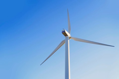 A towering wind turbine set against a vibrant blue sky in California, USA, showcasing renewable