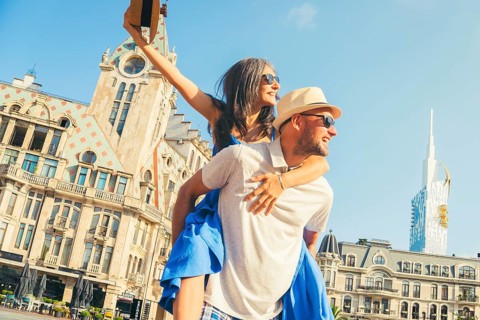 Beautiful young tourist couple having fun piggyback visiting Batumi Georgia. Tourists enjoying