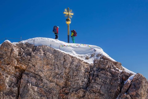 Summit cross with mountaineers on the Zugspitze summit 2962m with historic Munich house,