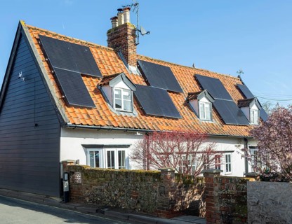 Monocrystalline solar photovoltaic PV panels on steep roof of historic cottage building, Wickham
