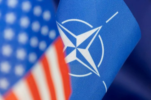 NATO flag, blurred in the foreground the US flag