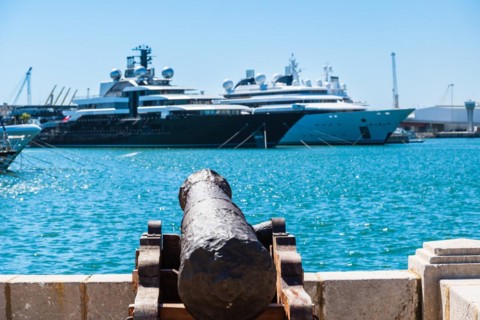 An old cannon in the harbour, luxury yachts at anchor in the background, Tarragona, Spain
