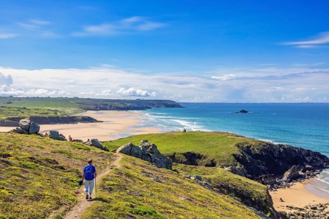 Man walking on a hiking trail on the French coast with a beautiful view of the sea on a sunny