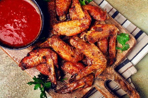 Fried in the oven, chicken wings, with spices, tomato sauce, on a cutting board, gray background,
