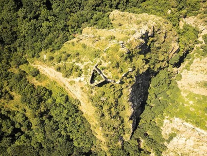 Aerial top down view of Armazi Fortress ruins on steep ridge with tilted rock formations and