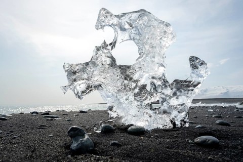 Ice, piece of ice with holes on the black sand beach, on the black lava beach Diamond Beach,