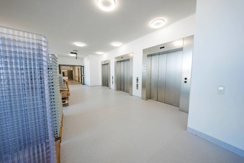 A modern hospital lobby with elevators and transport carts in bright surroundings, new Calw