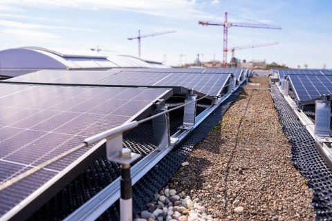 Photovoltaic panels on a roof near construction site cranes, PV installation. OBI Baumarkt,