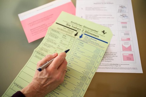 Voting, woman holding ballpoint pen, fills out ballot papers, votes, absentee ballot, official