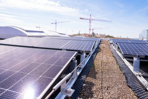 Solar panels on a roof near cranes in sunny skies, PV installation. OBI Baumarkt, Mühlacker,