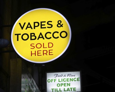 Sign for Vapes and Tobacco Sold Here outside shop dark at night, London, England, UK