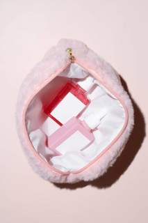 A soft, pink fur cosmetic bag is open to reveal two vibrant skincare bottles with droppers. The