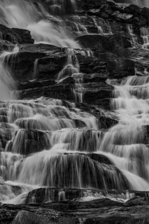 Mae Ya waterfall with cascading flowing water framed by lush tropical vegetation, black and white