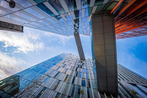 Looking up at modern Google buildings with reflecting windows and bridges under blue sky, Docklands