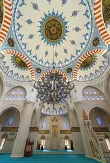 Interior view showcasing the decorated main dome, stained glass windows, a massive chandelier, and