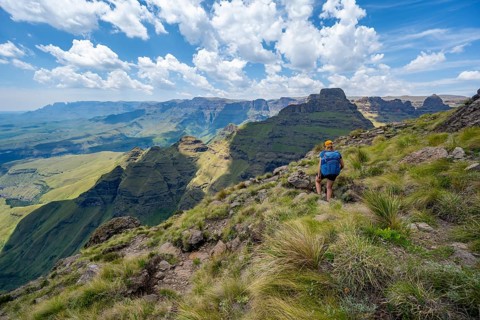Female mountaineer hiking trail to Cathedral Peak or Cathedralpiek or Mponjwana, Drakensberg,