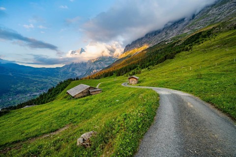 Road, alpine huts and alpine meadows, mountain landscape at sunset, summit of the Wetterhorn in the