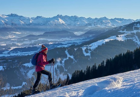 Nice and active senior woman snowshoeing in in the snow covered Allgaue alps above the valley of