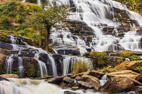 Mae Ya waterfall with cascading flowing water surrounded by lush tropical vegetation, near Doi