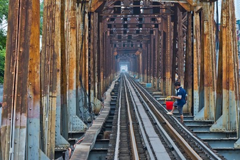 A Vietnamese State Railroad train crosses the Long Bien Railway Bridge across the Red River while a