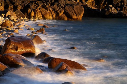 Stones, pebbles, pebbles, washed by water, waves, spray, motion effect, long exposure, evening