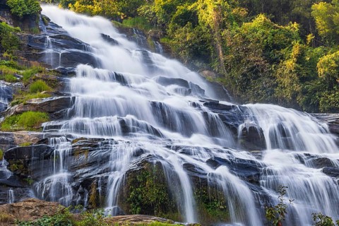 Mae Ya waterfall with cascading flowing water surrounded by lush tropical vegetation, near Doi