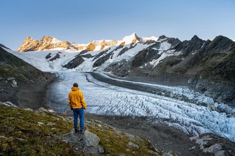 Young man in front of impressive high-alpine landscape, Finsteraarhorn and Agassizhorn mountain