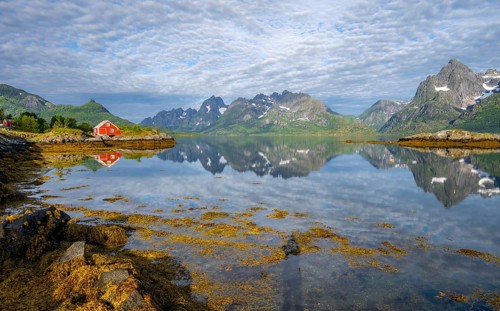 Red fishing hut on the shore, Rorbuer hut, picturesque fjord landscape at Raftsund fjord, mountains