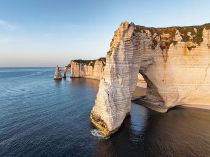 Aerial view of La Manneporte rock gate in the evening sun, behind it the Porte d'Aval rock