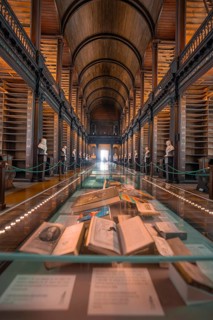 Historical library with exhibited books in a glass case and busts, Trinity Collage, Dublin, Ireland