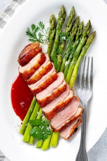 Roast duck breast, with asparagus, with red sauce, on a white plate, homemade, no people