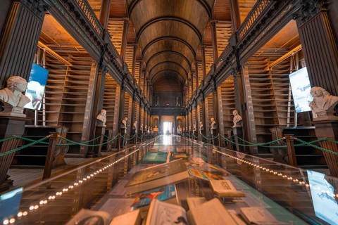 Impressive library with a long display case full of books and soft lighting, Trinity Collage,