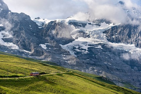 Jungfrau Railway to Jungfraujoch runs through green meadows, above the Kleine Scheidegg stop, rack