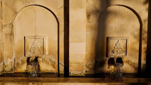 Two ancient stone wall fountains with running water in the evening sun, Meronas village, Meronas,