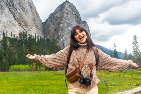 Woman standing with arms outstretched, cheerful and enjoying the stunning valley landscape of