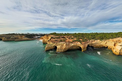 Drone view of cliffs above Benagil Cave in Algarve, Portugal, with limestone sea caves, turquoise