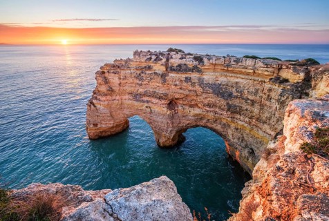 Sunrise at Praia da Marinha beach in Algarve, Portugal, with ocean cliffs, sea stacks and bright
