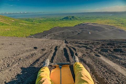 Travel person sandboarding on Cerro Negro, Nicaragua. View of man on Cerro Negro riding a sandboard