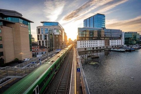 Panoramic view of a cityscape with tracks, train and modern buildings at sunset, Docklands, Dublin,