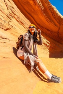 Woman traveler sitting in the desert sandstone formation of biidi the arch cave, enjoying her