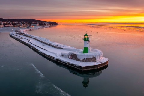 Ice covered Molenfeuer, frozen lighthouse, pier light on mole in Sassnitz harbour at sunrise in