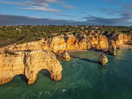 Aerial view of Praia da Marinha beach in Algarve, Portugal, with ocean cliffs, sea stacks and clear