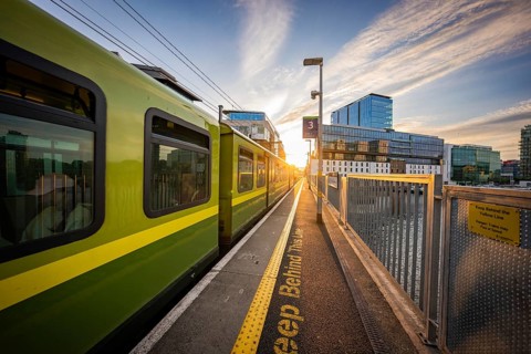 A train on the platform at sunset with modern buildings in the background, Dockland Dublin, Ireland